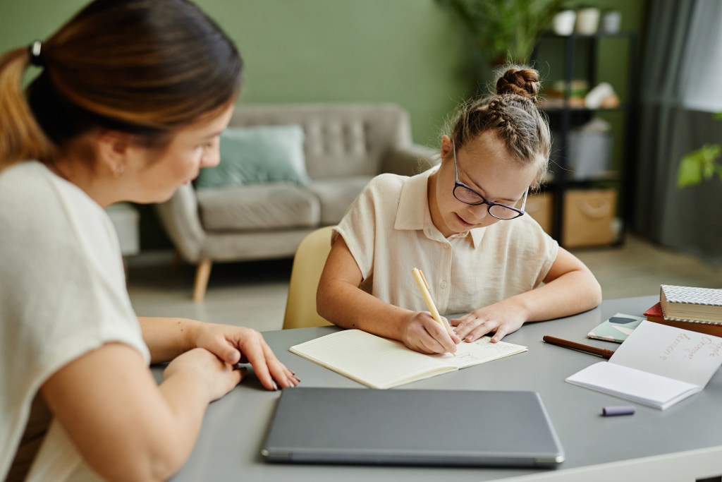 two women sitting at a table with notebooks and books