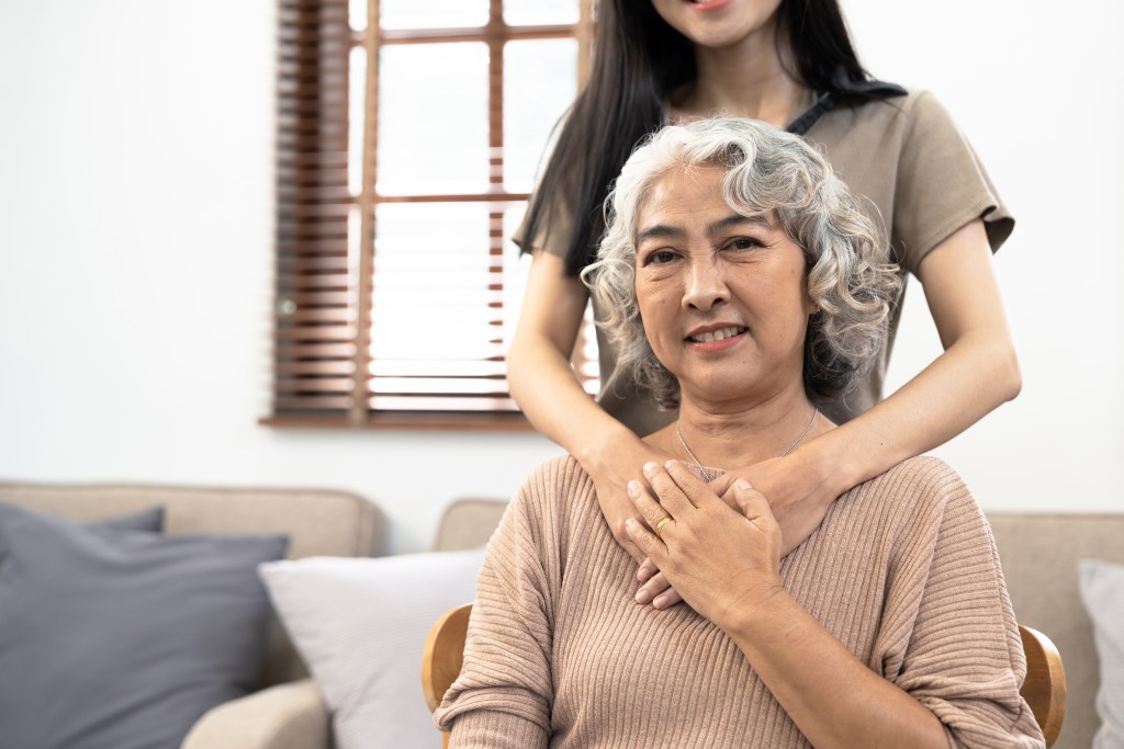 an older woman sitting in a chair with her hands on her chest