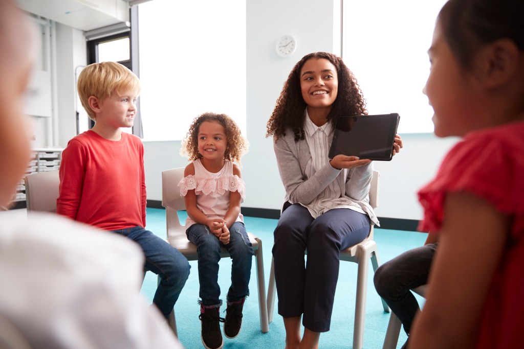 a woman sitting in a chair with a group of children